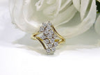 This is a 1ct total weight natural diamond waterfall style cluster ring in yellow gold with a white flowery background.