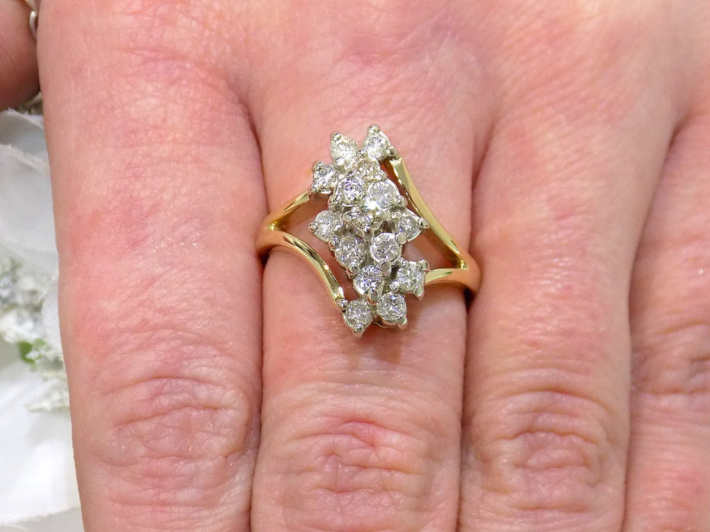 This is a 1ct total weight natural diamond waterfall style cluster ring in yellow gold shown on a ladies' finger.