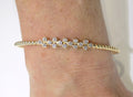 This is a women's.50ct total weight diamond flex bangle in 10K yellow gold on a ladies wrist with a white background.