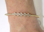 This is a women's.50ct total weight diamond flex bangle in 10K yellow gold on a ladies wrist with a white background.
