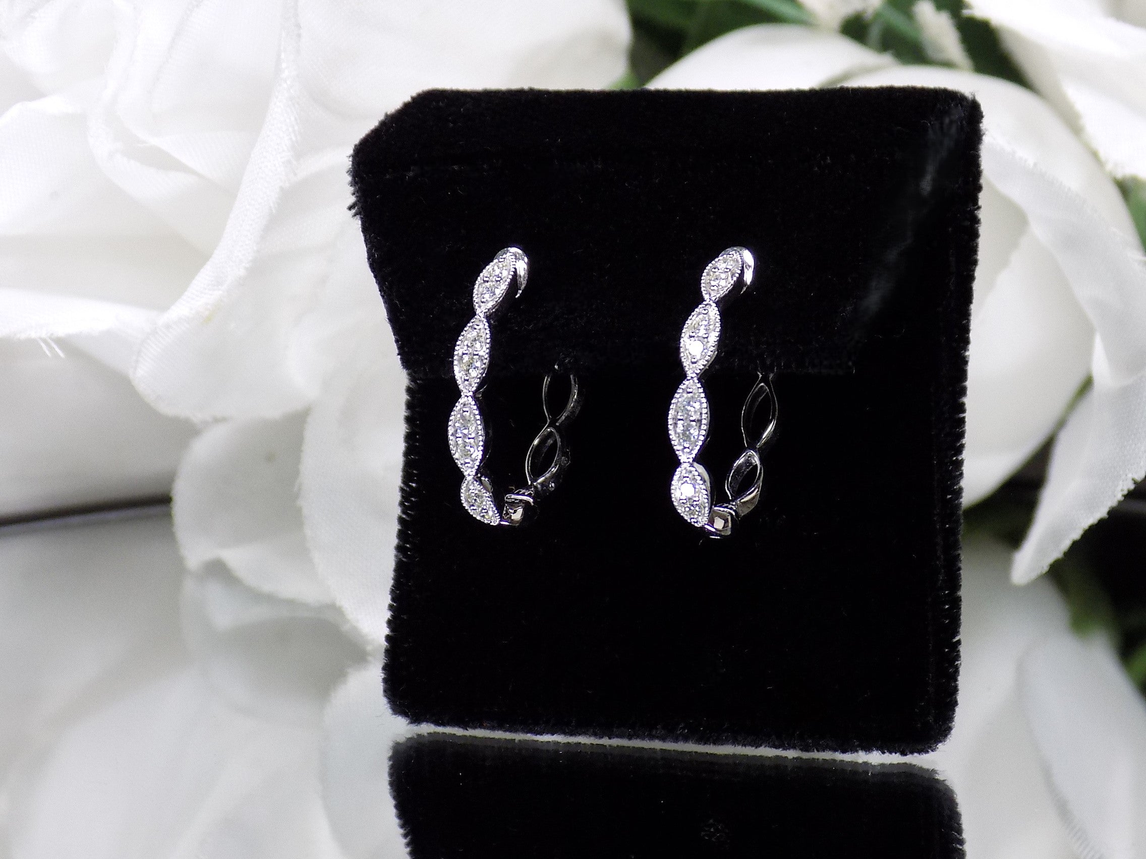 This is a pair of scalloped diamond hoop earrings in white gold.
