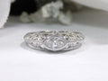 This is a bezel set marquise shape diamond set sideways in a white gold filigree ring with a white background.