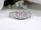This is a bezel set marquise shape diamond set sideways in a white gold filigree ring with a white background.