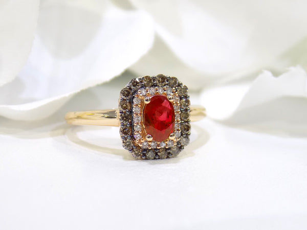 This is a women's effy brand ring with a .57ct natural oval shape ruby with a halo of natural white diamonds and a halo of chocolate diamonds on the outside for a total wight of .43ct in diamonds set in 14K rose gold with a white floral background.