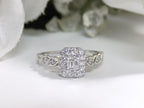 This is a .75ct natural emerald cut halo style ring with infinity style band in white gold with rose gold accents on the sides with a white background.