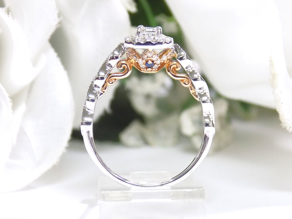 This is a side view of a .75ct natural emerald cut halo style ring with infinity style band in white gold with rose gold accents the side with a white background.