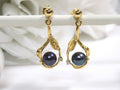 This is a pair of genuine black pearl earrings in yellow gold shown with a white background.