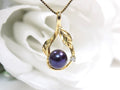 This is a fully restored to like new leafy designed black pearl and diamond pendant in yellow gold shown on a white background.