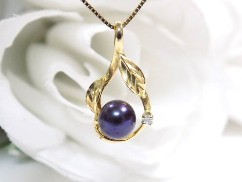 This is a fully restored to like new leafy designed black pearl and diamond pendant in yellow gold shown on a white background.
