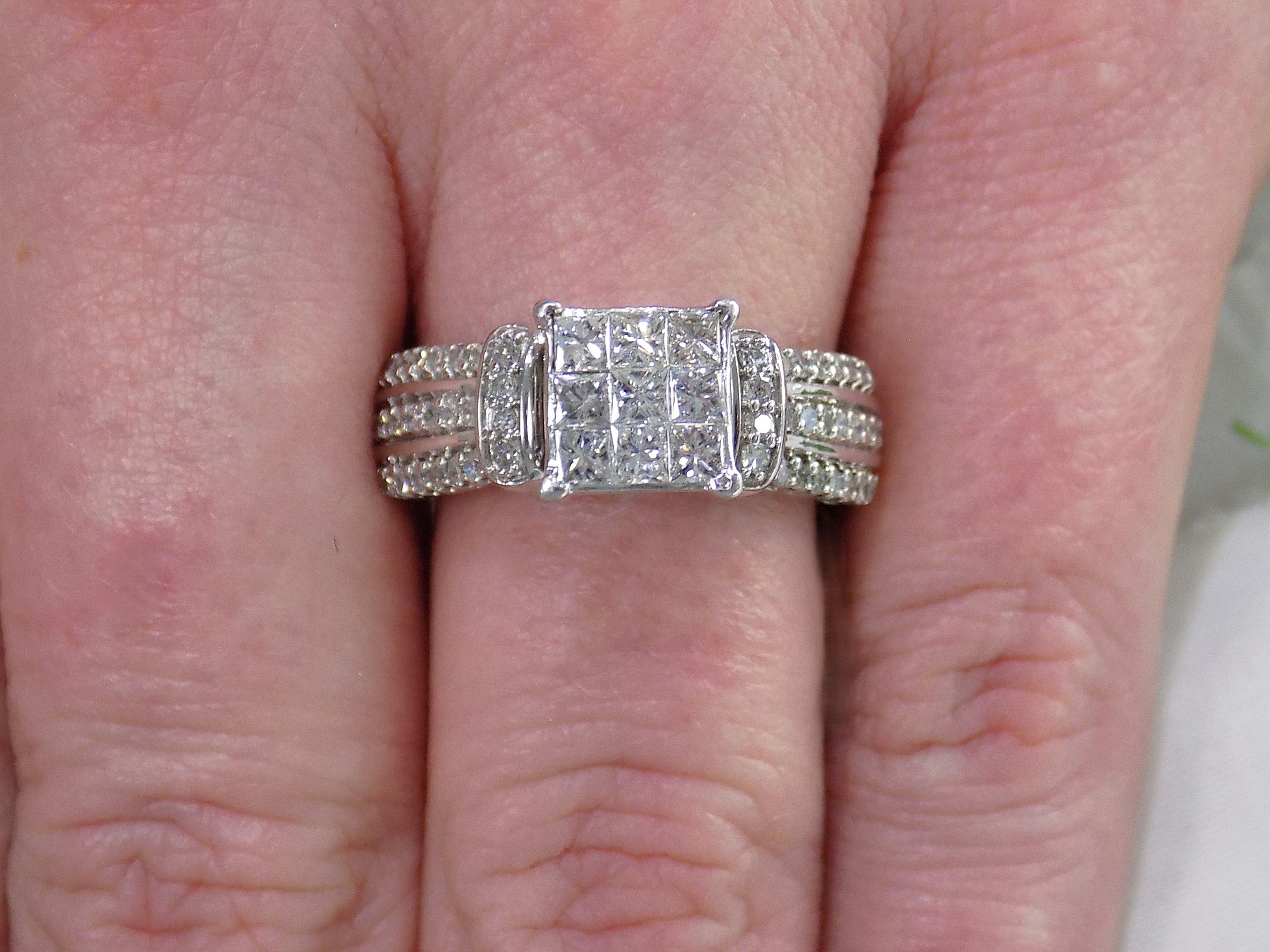This is an Estate ring with 1.00ct total weight invisible set diamond ring with natural princess cut and round diamonds in white gold on a ladies finger.