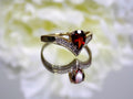 This is a pear shape garnet ring with diamond accents in yellow gold from our estate collection with flowery mirrored background.