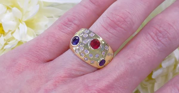 This is a women's estate ring with 2.50ct total weight ruby, sapphire, and diamonds set in 18K yellow gold on a ladies finger.
