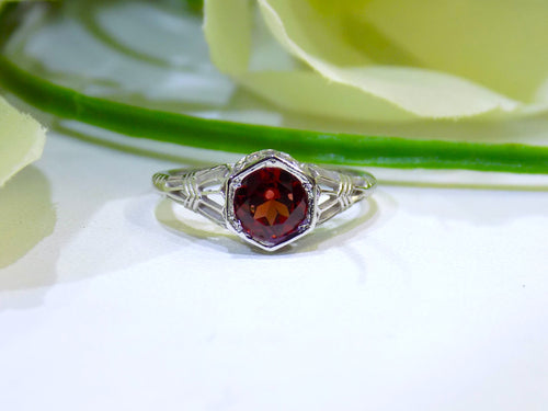This is a 1.00ct natural garnet ring in a filigree Victorian style in 10K white gold with a white and green background.