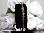This is a .50ct natural round brilliant diamond flex bangle in 10K yellow gold on a black display with a white floral background.