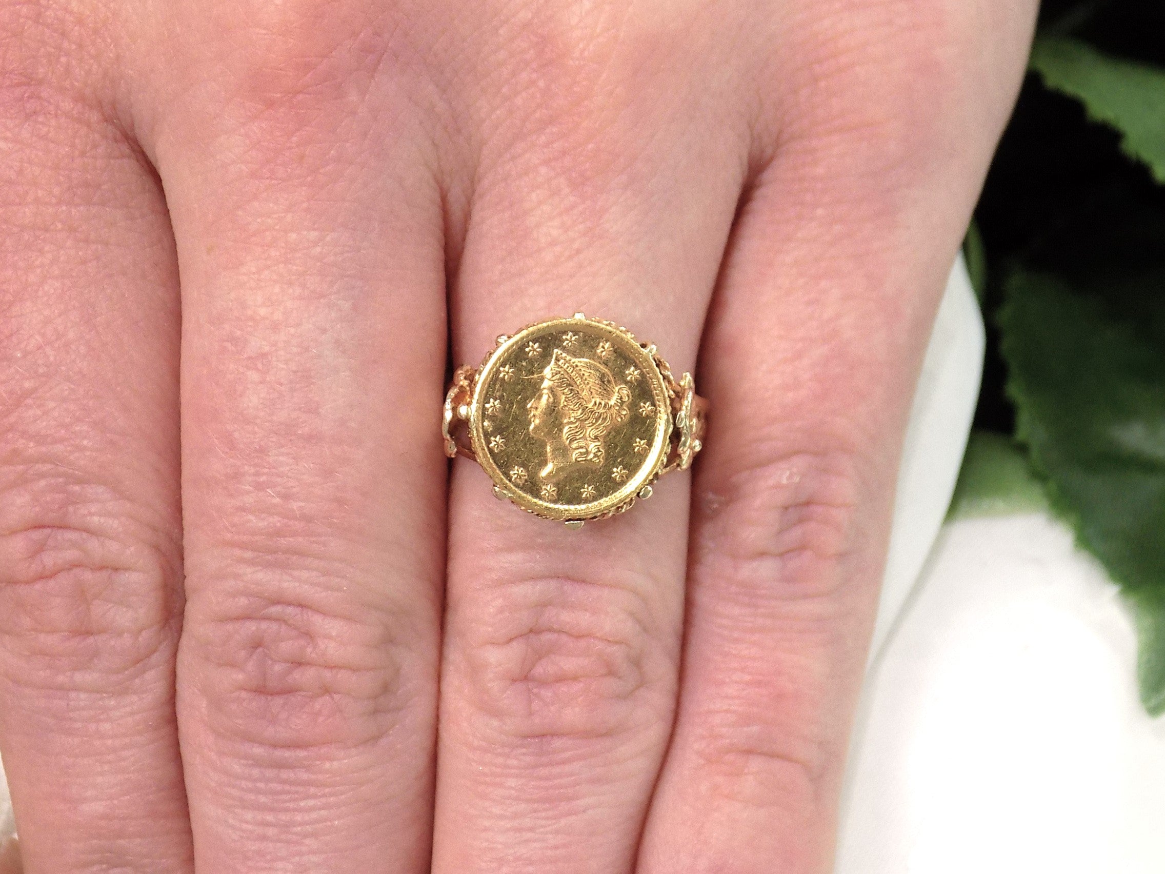 This is a women's US $1 gold coin ring dated 1853 and set in 14K yellow gold in great condition shown on a woman's finger.