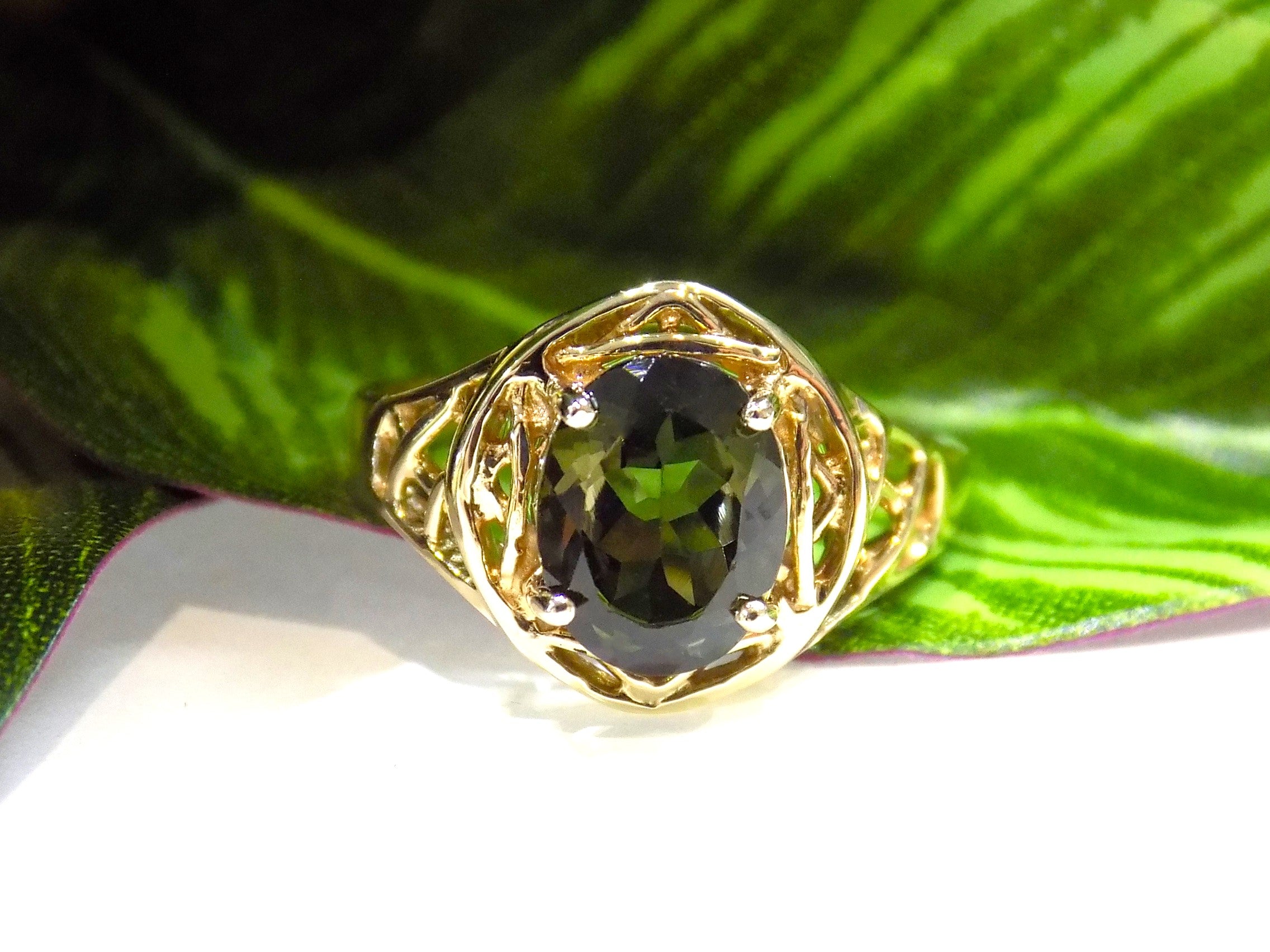 This is a women's natural green tourmaline ring with a 1.70ct genuine oval shape green tourmaline set in a filigree style mounting in 10K yellow gold with a green leaf background.