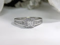 This is a halo style .50ct total weight natural princess cut diamond ring in white gold with white background.