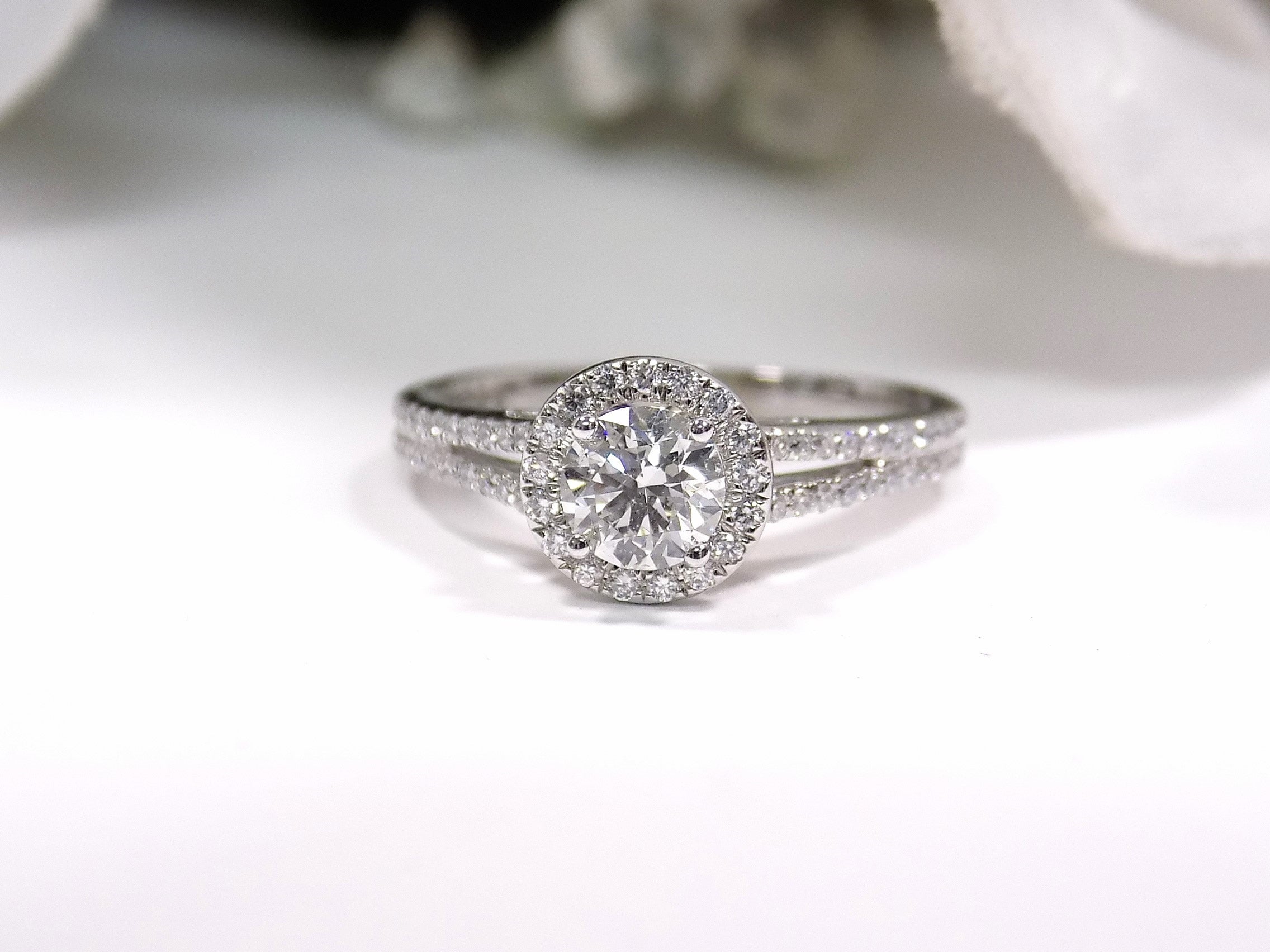This is a halo style natural .75ct tw round diamond ring in white gold with white background.