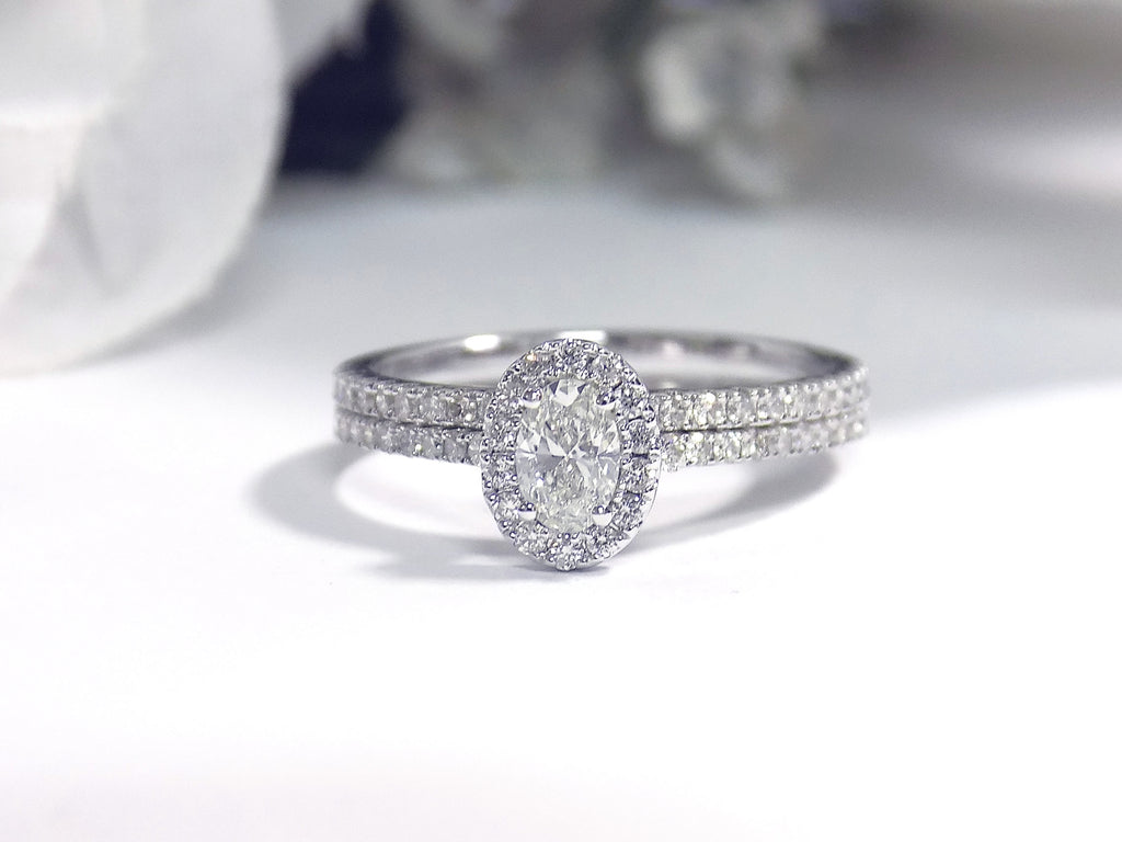This is a .73ct total weight 2-piece halo style oval shape natural diamond wedding set with engagement ring and matching band in white gold with a white background.