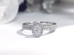 This is a .73ct total weight 2-piece halo style oval shape natural diamond wedding set with engagement ring and matching band in white gold with a white background.