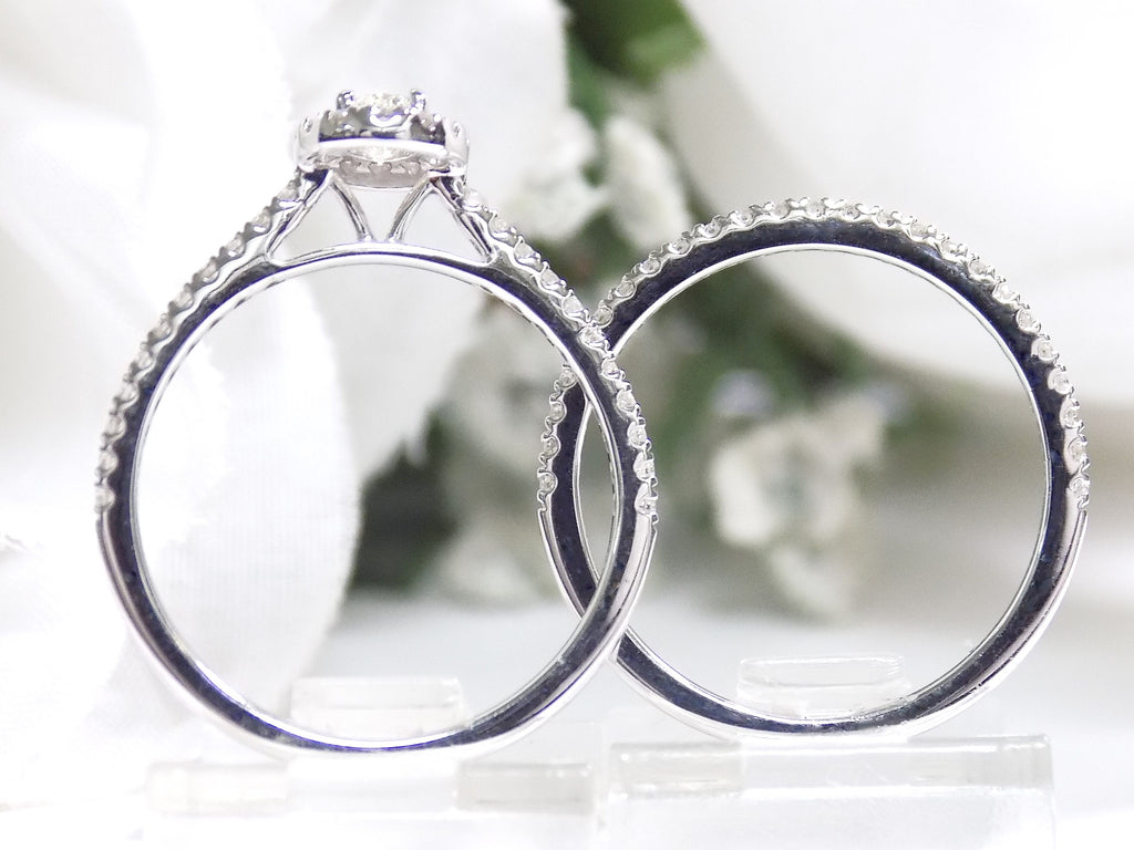 This is a side view of a .73ct total weight 2-piece halo style oval shape natural diamond wedding set with engagement ring and matching band in white gold with a white background.