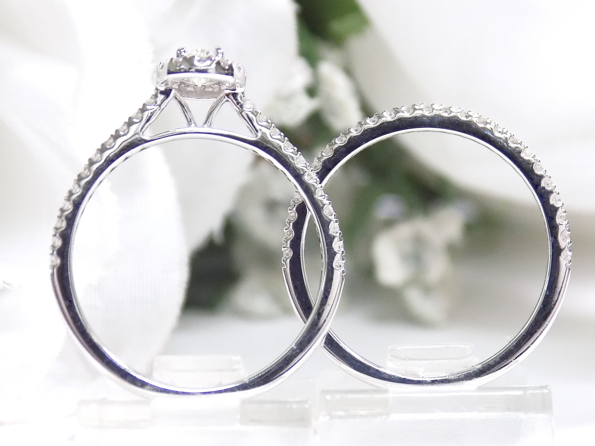 This is a side view of a .73ct total weight 2-piece halo style oval shape natural diamond wedding set with engagement ring and matching band in white gold with a white background.