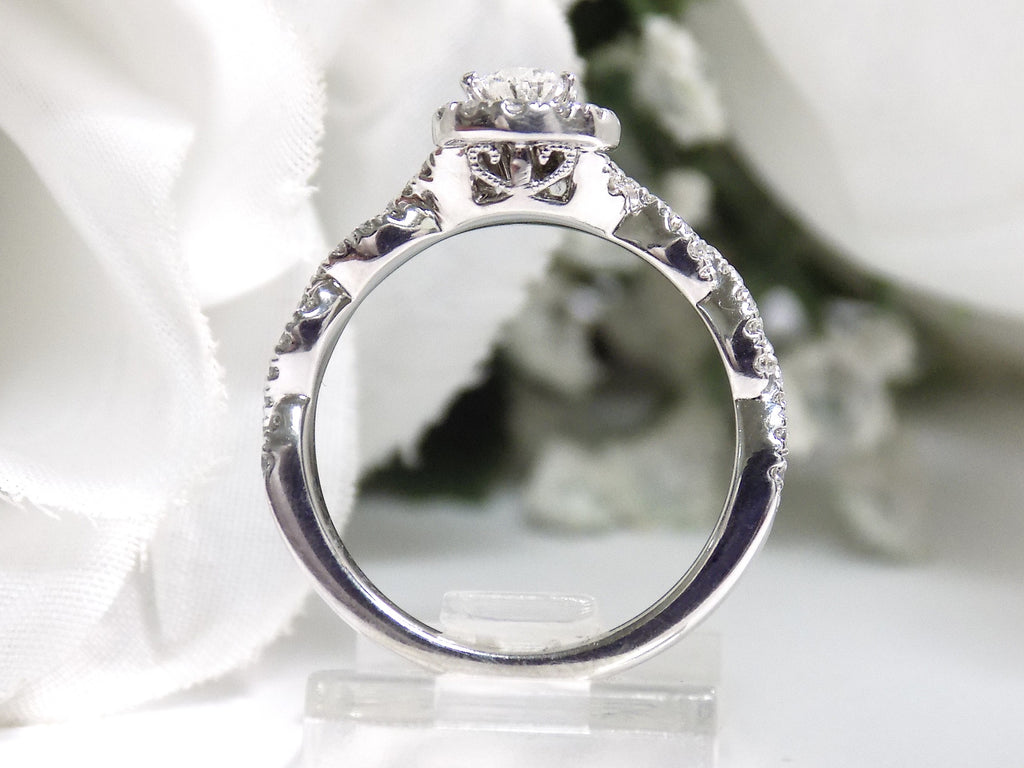 This is a side view of a halo style .82ct total weight natural pear shape diamond ring with infinity style band in white gold with a white background.