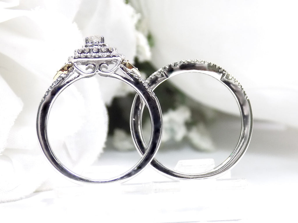 This is a halo style 2-piece wedding set ring with matching band in white gold with yellow gold accents shown from the side on a white background.