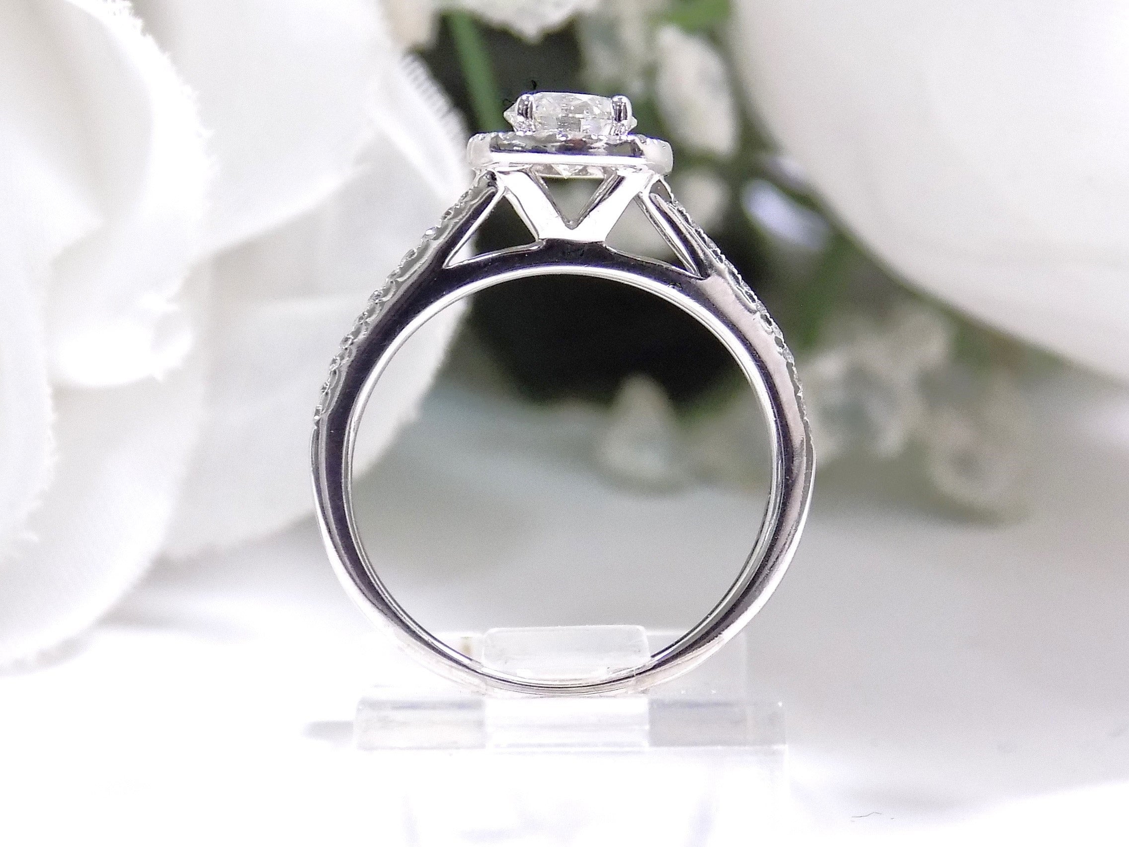 Halo style natural diamond ring in white gold with white background shown from the side.