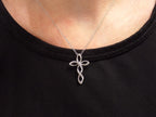 This is an infinity style natural diamond cross necklace in white gold on a ladies neck.
