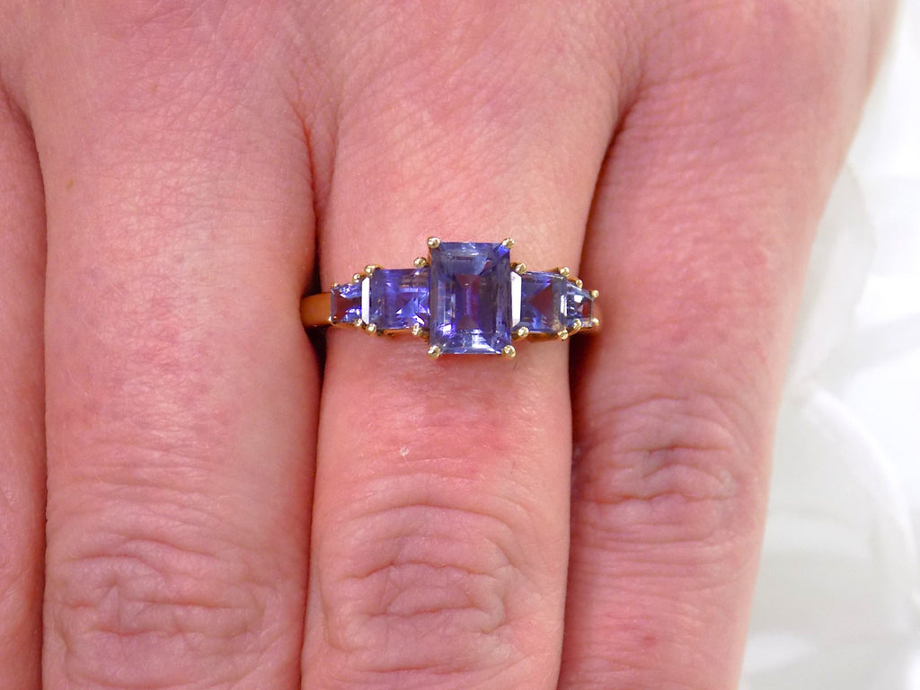 This a 5-stone genuine emerald cut iolite ring in yellow gold from our estate collection in like new condition shown on a woman's finger.