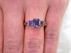 This a 5-stone genuine emerald cut iolite ring in yellow gold from our estate collection in like new condition shown on a woman's finger.