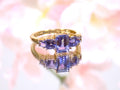 This a 5-stone genuine emerald cut iolite ring in yellow gold from our estate collection in like new condition shown with a pink flowery background.