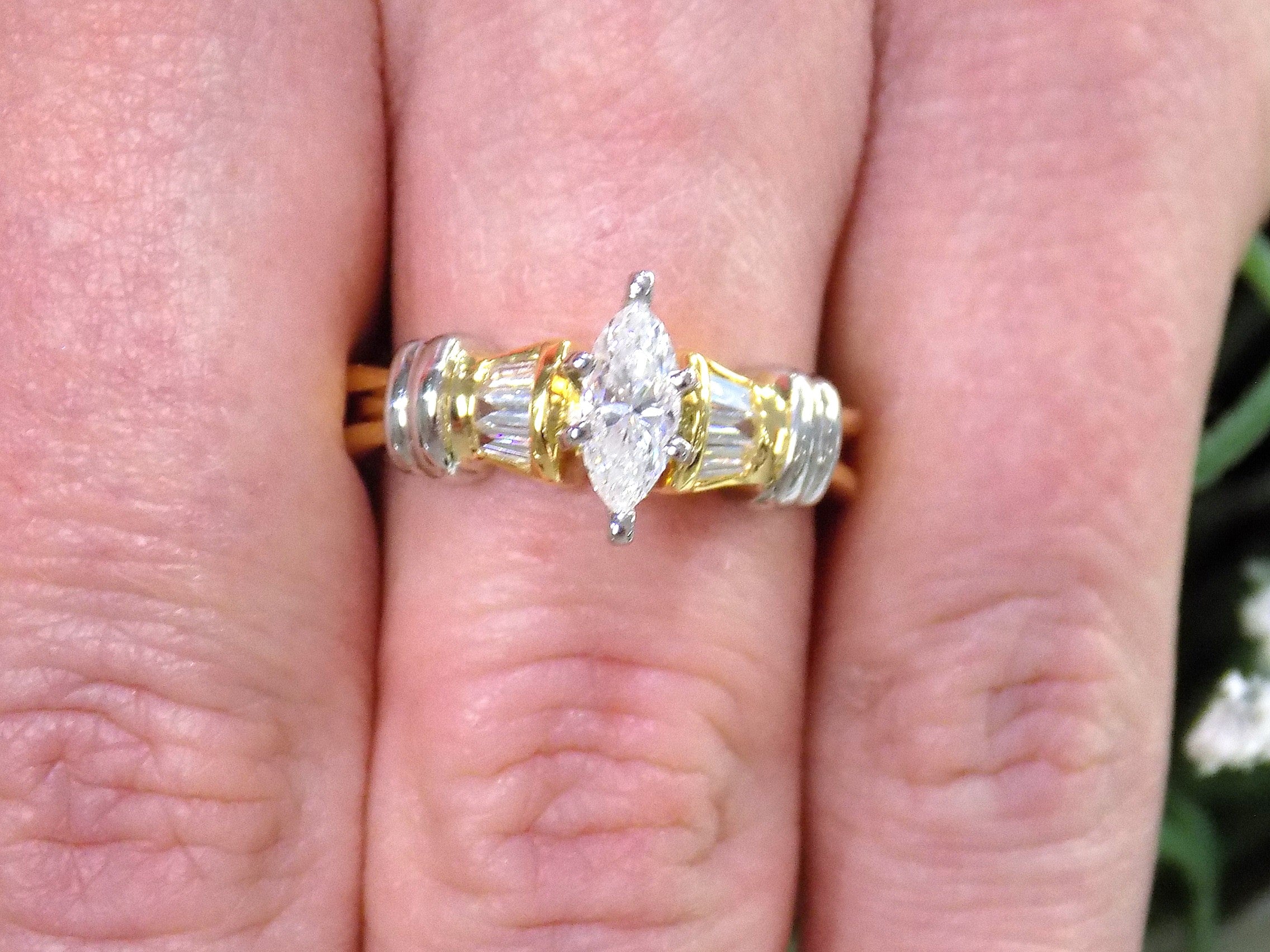 This is a .80ct total weight natural diamond ring baguette diamond accents in 2-tone 18K yellow gold and platinum shown on a woman's finger.
