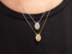 This is two .25ct natural center marquise diamond necklace with a halo of .10ct round diamonds one is in 14K yellow gold and the other is in 14K white gold on a ladies neck with a black shirt.