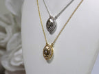 This is two .25ct natural center marquise diamond necklace with a halo of .10ct round diamonds one is in 14K yellow gold and the other is in 14K white gold on a white display neck from a side view.