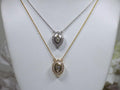 This is two .25ct natural center marquise diamond necklace with a halo of .10ct round diamonds one is in 14K yellow gold and the other is in 14K white gold on a white display neck.