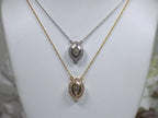 This is two .25ct natural center marquise diamond necklace with a halo of .10ct round diamonds one is in 14K yellow gold and the other is in 14K white gold on a white display neck.