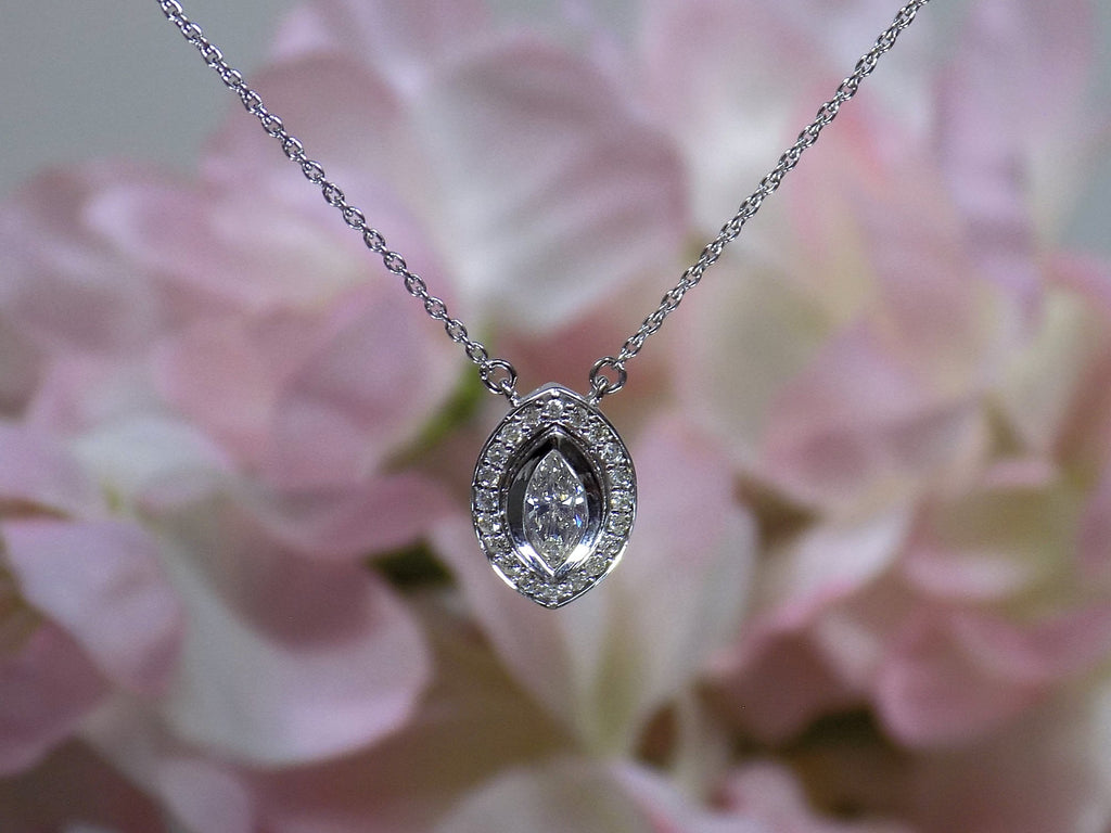 This is a .25ct natural center marquise diamond necklace with a halo of .10ct round diamonds in 14K white gold with a pink floral background.