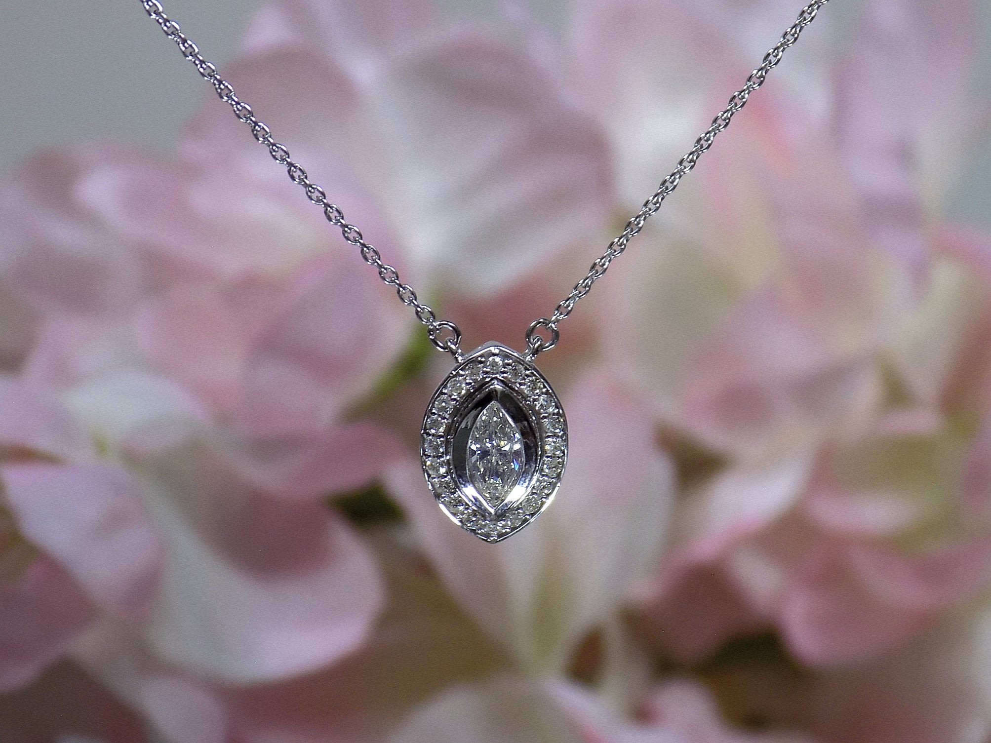 This is a .25ct natural center marquise diamond necklace with a halo of .10ct round diamonds in 14K white gold with a pink floral background.