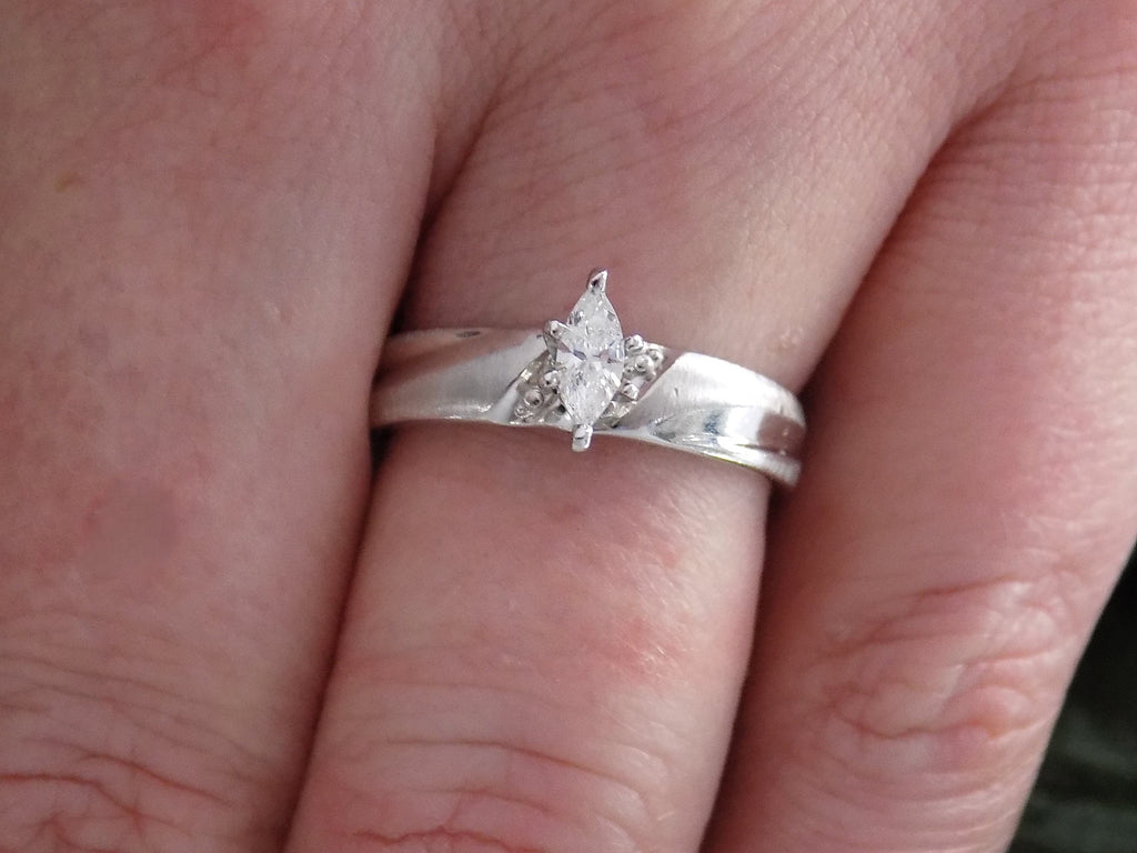 Preowned white gold ladies small marquise shape diamond ring on ladies' shown on a woman's finger.