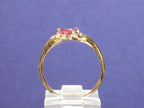 This is a .32ct total weight marquise shaped natural ruby and diamond ring in 10K yellow gold side view with a bluish/purple background.