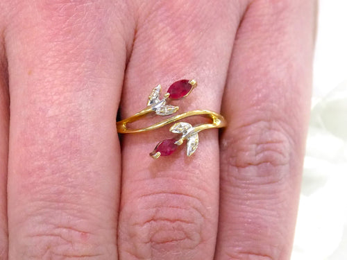 This is a .32ct total weight marquise shaped natural ruby and diamond ring in 10K yellow gold on a woman's finger.