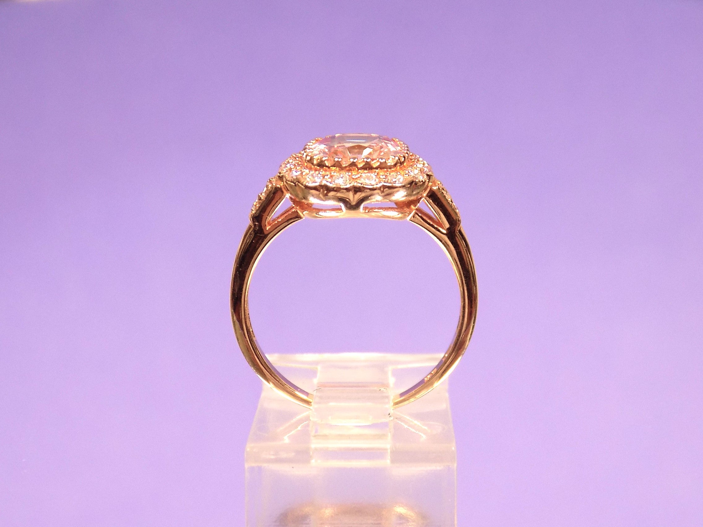 This is a women's ring with 1.94ct natural cushion cut morganite in the center surrounded by .30ct in natural round diamond accents in 14K rose gold  from a side view with a purple background.