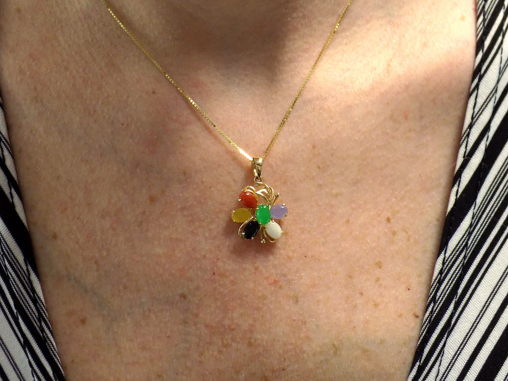 This is a fully restored to like new woman's multicolor jade & onyx pendant in yellow gold shown on a woman's neck.