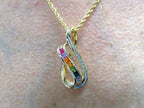 This is a women's slide pendant with 1.38ct total weight natural multicolor natural sapphires and .12ct total weight natural round diamonds in 14K yellow gold on a women's neck.