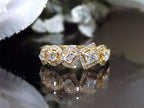 This is a multi shape natural diamond ring including a pea shape, round brilliant, emerald cut, princess cut and oval shape all surrounded by round diamond accents in 10K yellow gold on a black background.