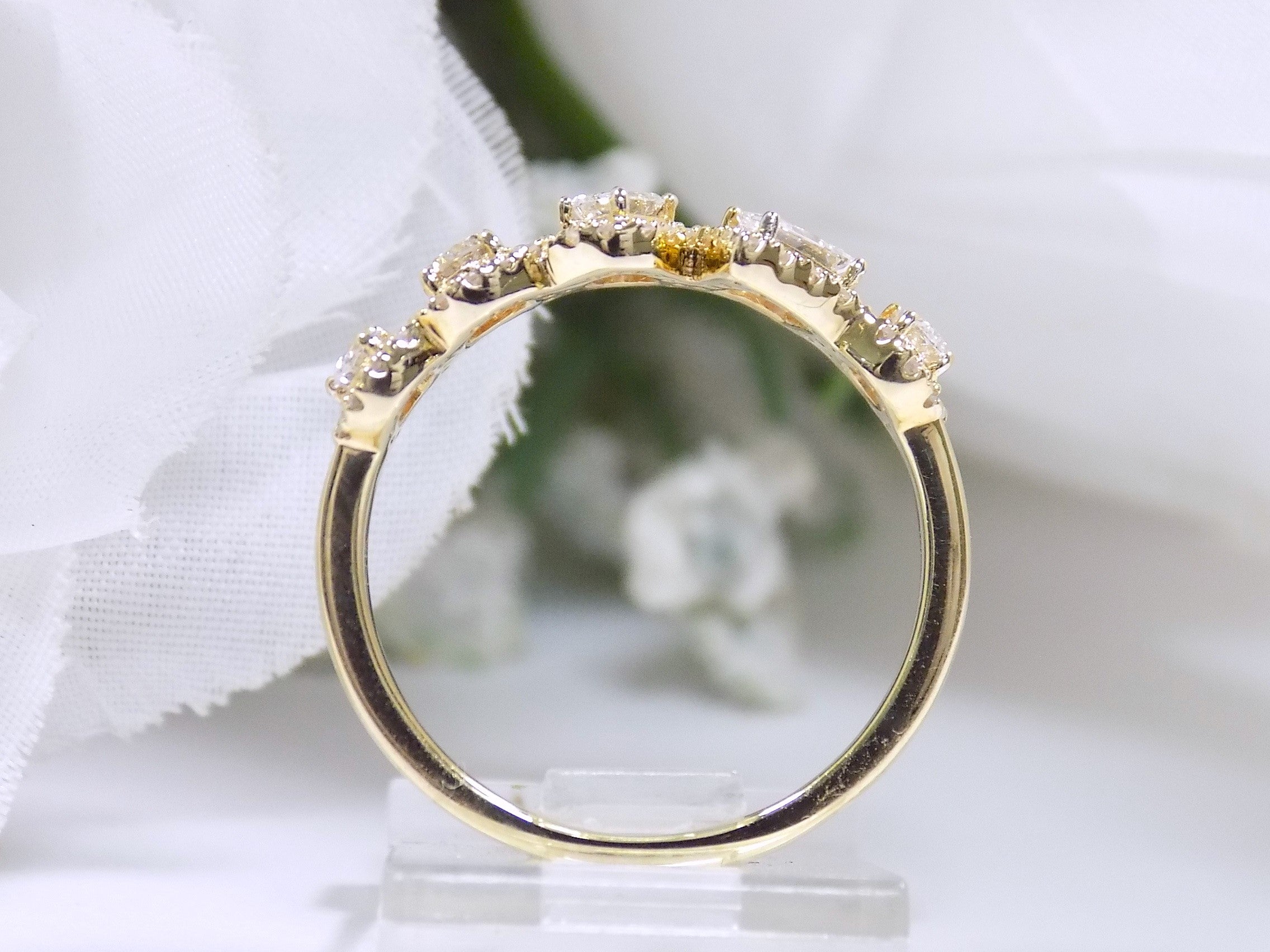 This is a multi shape natural diamond ring including a pea shape, round brilliant, emerald cut, princess cut and oval shape all surrounded by round diamond accents in 10K yellow gold side view.