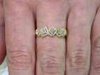 This is a multi shape natural diamond ring including a pea shape, round brilliant, emerald cut, princess cut and oval shape all surrounded by round diamond accents in 10K yellow gold on a ladies finger.