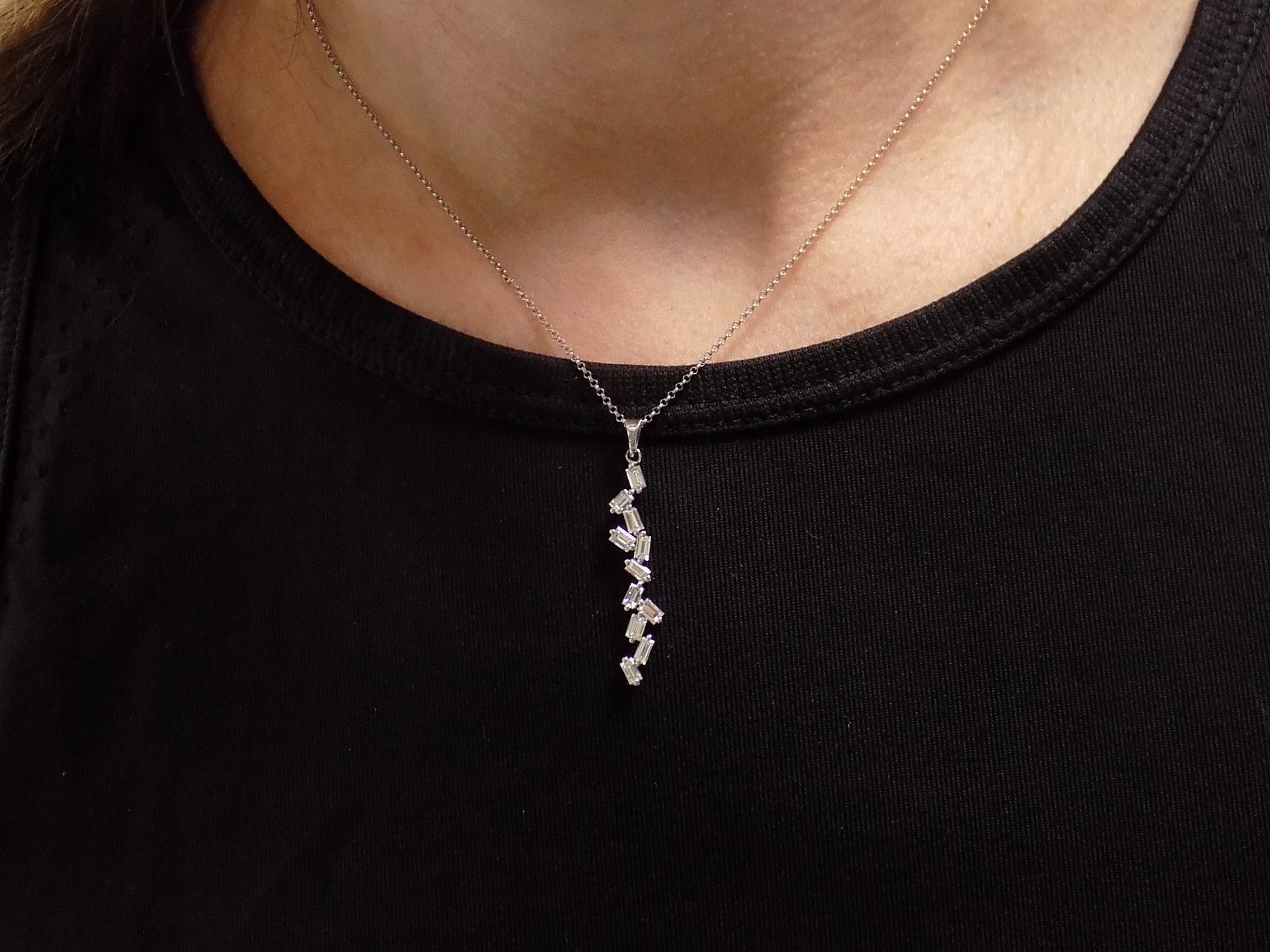 This is a custom made .91ct natural baguette diamond necklace in 18K white gold on a ladies neck with a black shirt.